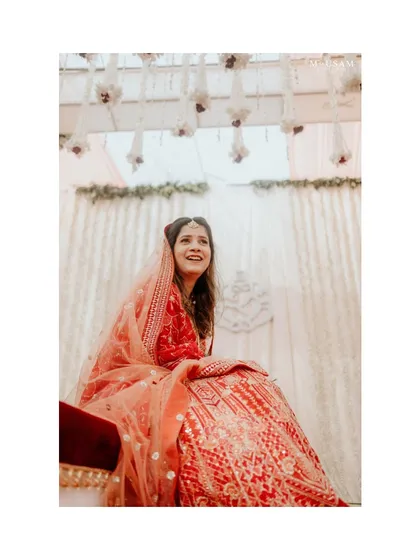 A candid portrait of the bride, looking up with a beautiful, genuine smile. Seated at the mandap, this shot captures a moment of pure happiness and anticipation.
