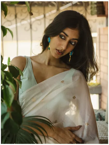 Using natural elements like plants to frame the subject adds depth and a sense of intimacy to the portrait. The soft light is perfect for this gentle, elegant look.