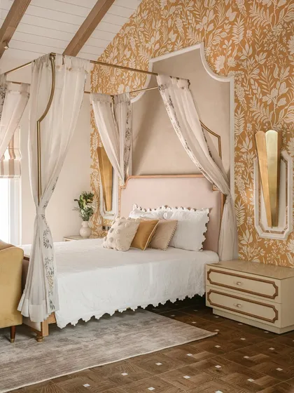For this bedroom, we created a sanctuary that blends vintage romance with contemporary calm. The custom four-poster bed, draped in sheer fabric, becomes the centerpiece, complemented by warm golden wallpaper and bespoke nightstands, crafting a visual lullaby for the senses.