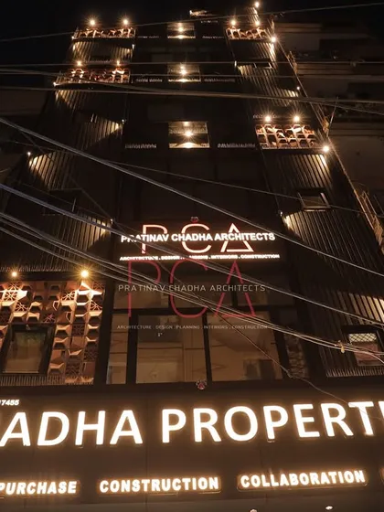 A wide shot of the Chadha Properties office at night, capturing the ambient street lighting and the building's prominent, glowing facade.