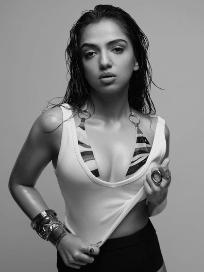 The same edgy look for Ahsaas Channa in black and white. This version emphasizes the textures of the wet hair, the tank top, and the bold metallic jewelry.