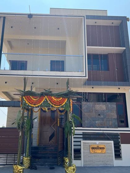 The completed facade of Mr. Kantraj's residence, a modern 30x50 duplex house. The design features a large cantilevered balcony with a glass railing, creating a bold and contemporary statement.