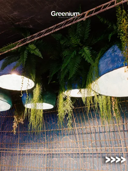An artistic rooftop design featuring dark blue pendant lights intertwined with hanging artificial plants. This creates a moody and dramatic effect, perfect for an evening lounge or bar.