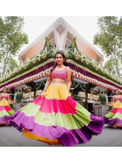 A vibrant, multi-colored lehenga designed for a fun-filled Mehendi ceremony. The twirl-worthy skirt and sequined pink crop top create a playful yet stunning look for our bride Varsha.
