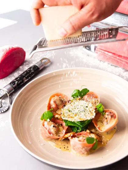 I believe in fresh ingredients and handmade quality. Here, I'm grating fresh parmesan over my beetroot-infused ravioli.