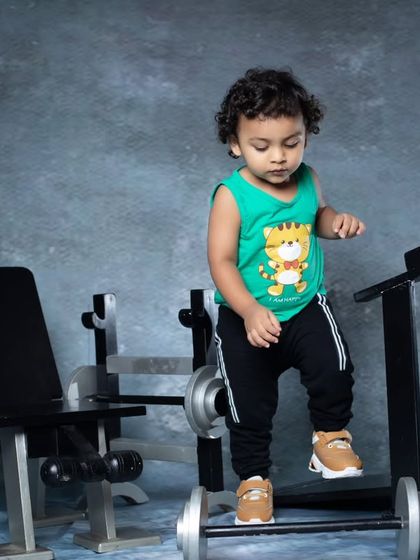This little one is getting a feel for the gym equipment, standing on the treadmill with a curious expression.