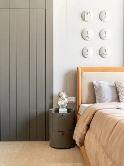 This master bedroom embodies minimalist luxury, featuring a warm neutral palette of beige, taupe, and muted grey, complemented by rich textures. The vertical paneling with a concealed door detail ensures a seamless, expansive look.