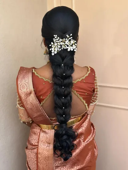 A beautiful messy braid adorned with a delicate baby's breath accessory. This is a romantic and modern hairstyle, perfect for an engagement or pre-wedding event.