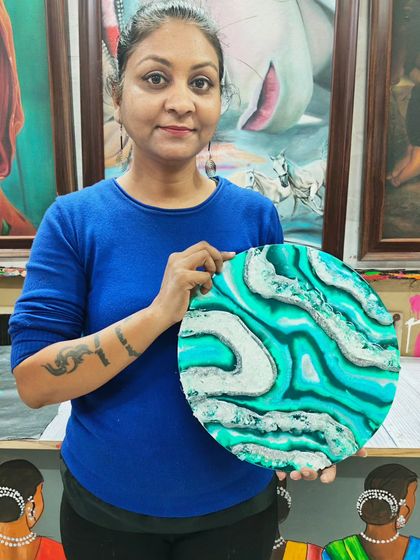 A student proudly displays her geode-inspired resin art. This piece features beautiful turquoise and white patterns, mimicking natural stone formations.