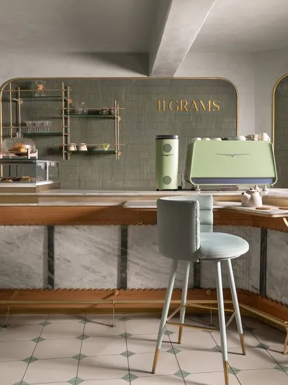 Another view of the bar, showing the sage green equipment and the brass "11 Grams" lettering against a textured tile backdrop.