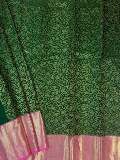 A close-up of the intricate floral brocade weaving on the green saree.