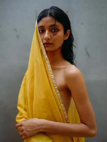 A portrait from the yellow drape series where the fabric veils part of the model's face. The direct gaze through the fabric creates a compelling and intimate connection.