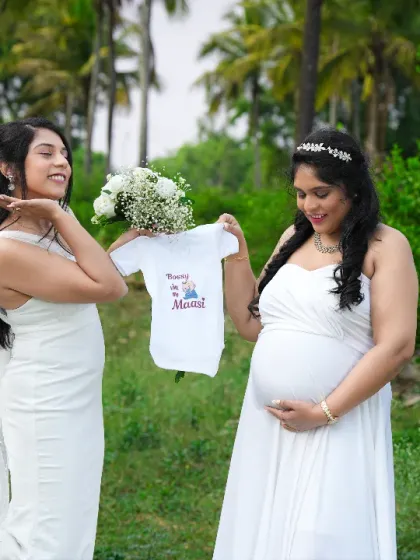 A sweet moment between friends, holding up a "Tia in the making" onesie. A perfect way to celebrate the aunt-to-be.