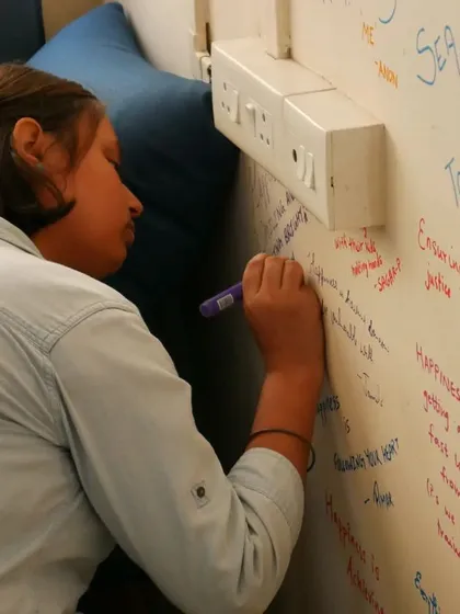 A close-up of a volunteer writing on the wall, a symbol of our collective spirit.