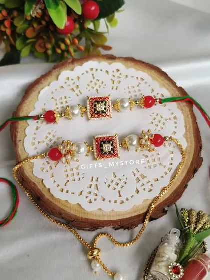 An exclusive, beautifully crafted couple's Rakhi set for your Bhaiya and Bhabhi, featuring red and green meenakari work.