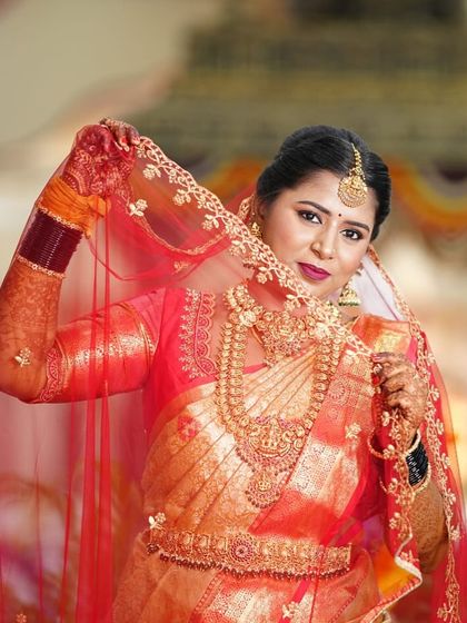 A playful and elegant pose. The sheer red veil adds a touch of drama, while her antique gold jewellery, including the choker, haram, and maang tikka, remains the star of the show.