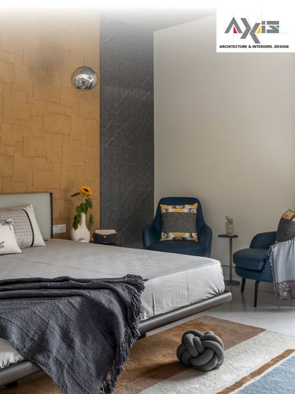 Texture and color come together in this cozy bedroom. The combination of a stone-textured accent wall, a comfortable bed, and plush armchairs creates a perfect corner for unwinding after a long day.