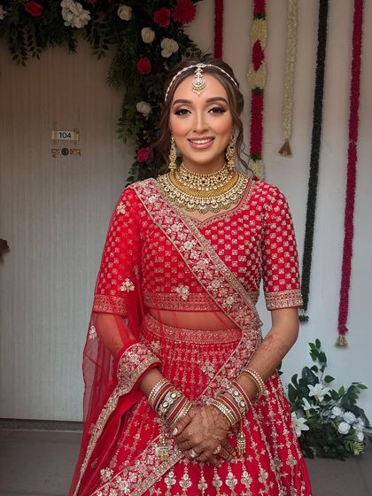 A beautiful bride in her red lehenga. I styled her hair in a soft, wavy half-updo, complemented by a traditional headband-style matha patti.