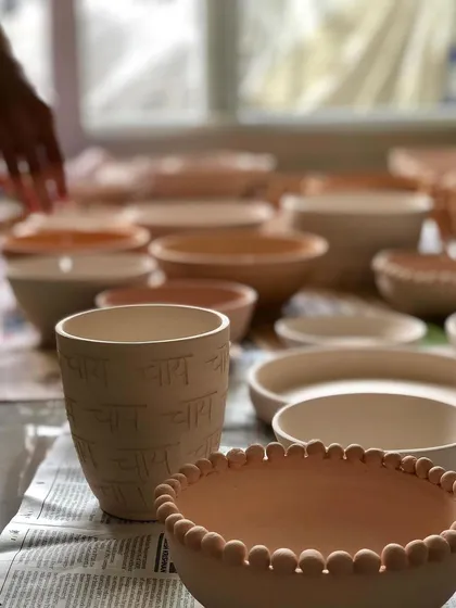 A view of my studio table filled with freshly made, unfired pottery. You can see a variety of bowls and a 'Chai' cup waiting for the next stage of the process.