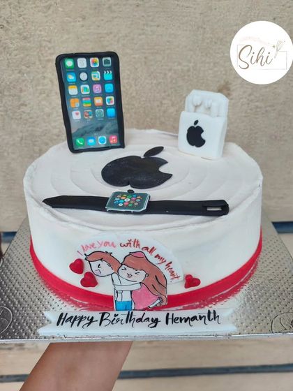 Tech, but make it cute. This cake is for the ultimate Apple fan, featuring a fondant iPhone, AirPods, and an Apple Watch, along with a sweet hand-drawn couple.