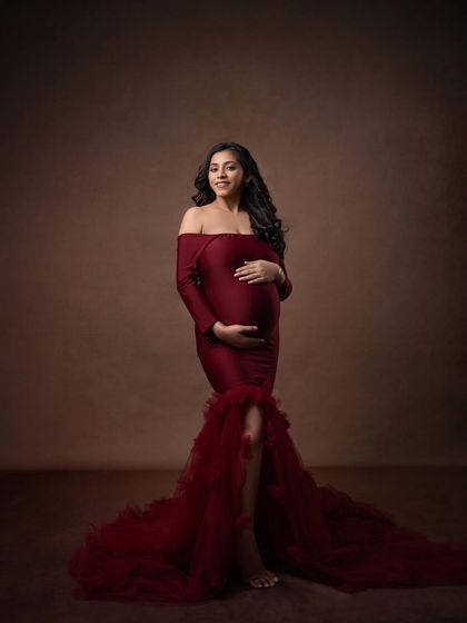 This elegant red gown looks stunning against a classic painterly brown backdrop. The full-length shot showcases the dramatic train and timeless silhouette.