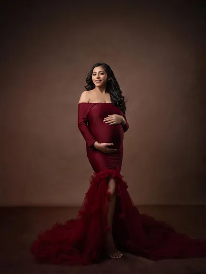 This elegant red gown looks stunning against a classic painterly brown backdrop. The full-length shot showcases the dramatic train and timeless silhouette.