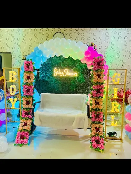 An indoor baby shower setup with a swing, a green wall backdrop, and 'Boy' 'Girl' marquee letters for a gender reveal.