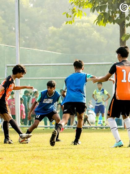 A group of players from both teams challenge for the ball in a crowded part of the field.