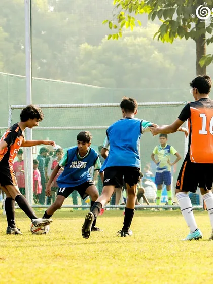 A group of players from both teams challenge for the ball in a crowded part of the field.
