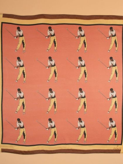 A flat-lay of a pink pocket square with a repeating golfer motif, showing the full pattern and color.