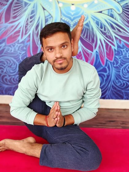 A seated pose with one leg behind the head, demonstrating deep hip rotation and flexibility.