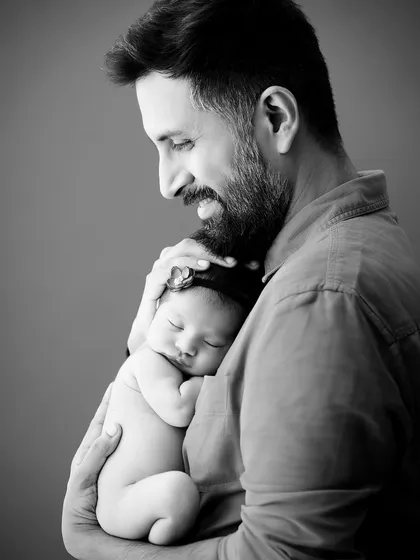 Sometimes, the most powerful emotions are captured without color. This black and white portrait of a father holding his newborn close emphasizes the profound connection and tenderness of their first moments together, a key feature of our moody portrait sessions.