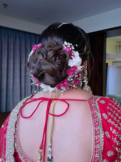 A detailed shot of a textured bridal bun adorned with fresh pink and white flowers and baby's breath.