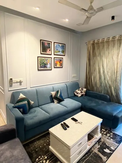 In this project, a comfortable teal L-shaped sofa is set against a wall with classic molding, adding a layer of texture and sophistication. This shows how I blend contemporary furniture with timeless architectural details for a richer look.