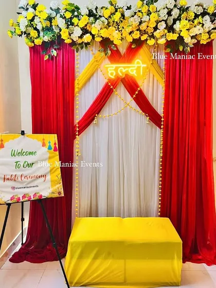 A striking Haldi setup with a red, white, and yellow color scheme. The design features a 'Haldi' neon sign and a welcome easel, creating a bold and beautiful look.