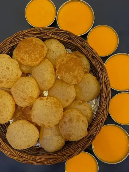 A basket of fluffy, golden-brown puris served with Aamras (mango pulp), a seasonal delicacy.