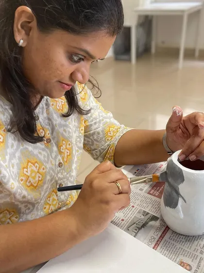 A close-up of the penguin planter painting in progress, showing the focus and detail involved.