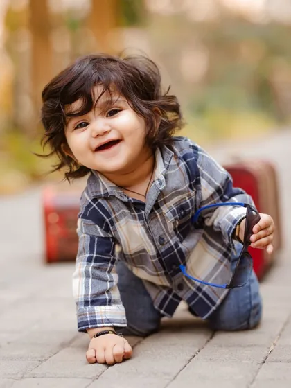 The adventure of learning to crawl. This candid outdoor photograph captures a genuine moment of exploration and happiness, using natural light to create a warm, timeless feel.