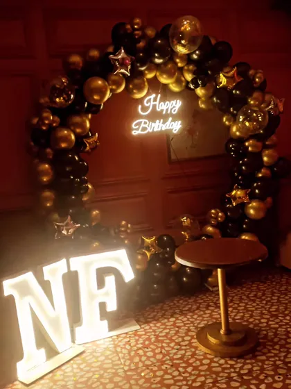 A chic black and gold birthday ring decoration, complete with a neon sign and marquee letters for initials.