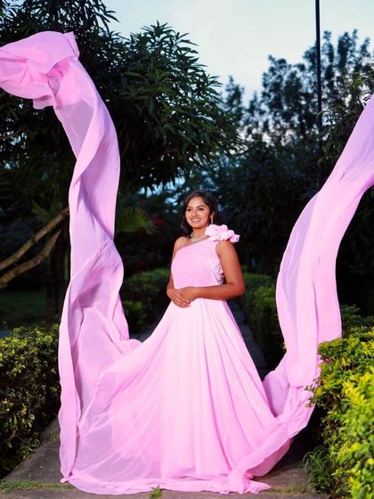 This shot captures the full effect of the pink infinity gown's long trails, creating a beautiful, wing-like effect in an outdoor setting.