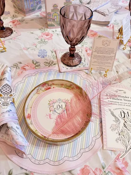 A close-up of the exquisite table setting, featuring custom monogrammed plates, striped placemats, and a delicate pink feather.