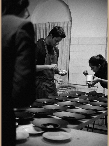 A black and white shot of my team plating dishes for the saree exhibition dinner, showing the focus and precision required.