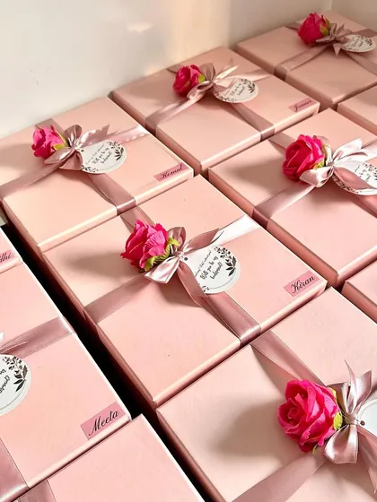 A beautiful array of bridesmaid boxes, each personalized with a name sticker and finished with a delicate artificial rose and a proposal tag.