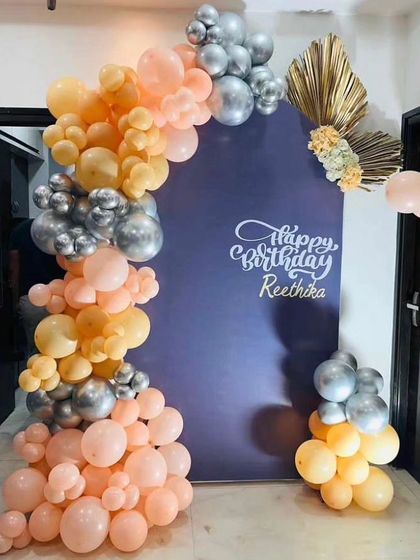 A sophisticated birthday backdrop with a personalized name, featuring a peach, gold, and silver balloon arch.
