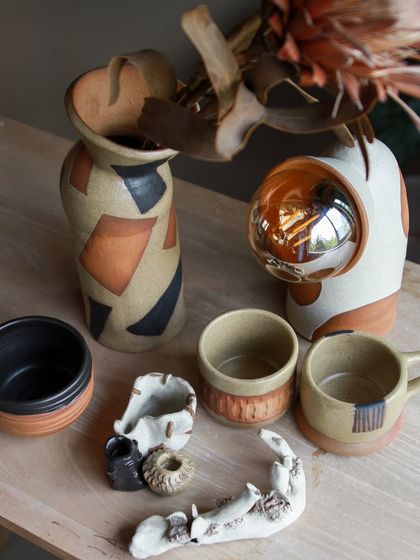 An artistic collection featuring an astronaut themed lamp, a carved ashtray, and a vase with bold, geometric patterns.