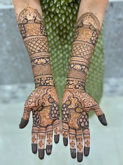 An elegant engagement mehendi with graceful peacock motifs on the palms and forearms.