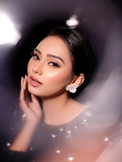 A dreamy and artistic shot of a model in a black sequined top, with soft, glowing makeup.