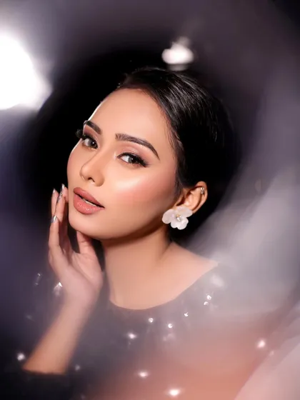 A dreamy and artistic shot of a model in a black sequined top, with soft, glowing makeup.