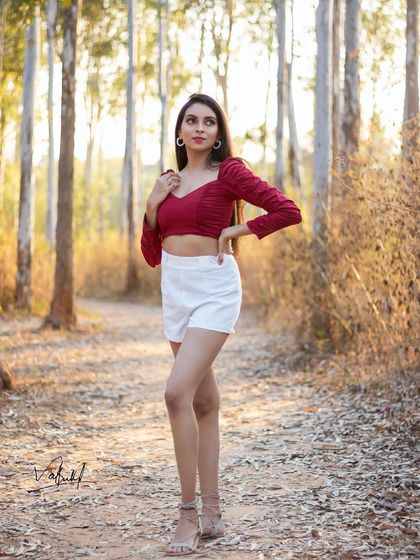 A full-length portrait taken during a golden hour shoot in the woods. The warm light filtering through the trees creates a beautiful, serene atmosphere that highlights the model's graceful pose.