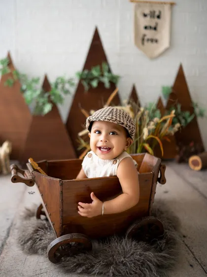 A happy baby boy in a wooden wagon, part of a "wild and free" adventure theme.